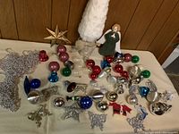 Full assortment of Christmas decorations including the small white tree, angel, bead garlands, and various colored glass ornaments