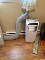 Full view of white ForestAir portable AC connected to flexible exhaust hose