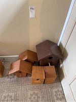 Overall view of five small wooden bird houses arranged on a patterned tiled floor against a beige wall.