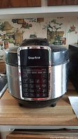 Front view of Starfrit electric pressure cooker showing the model number 024600 and digital control panel with various cooking options.