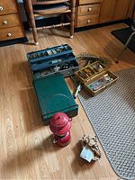 Overview of lot on wooden floor showing multiple tackle boxes, fishing net, red lantern, and green stove case