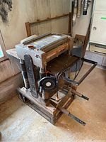 Front perspective of planer mounted on metal stand with dust hoses attached