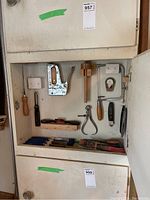 Cabinet with hand tools arranged inside including stapler, saws, caliper, dividers, files and other cutting tools.