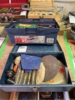 Photo showing the opened blue toolbox with various tool accessories inside including drill bits, polishing pads, and sanding discs.