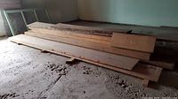 Long planks stacked on concrete floor in crawl space