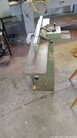 Side view of entire green cast-iron jointer on base with fence assembly