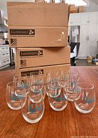 Three stacked cardboard boxes labeled Luminarc on kitchen counter with 12 stemless wine glasses arranged in front, showing the lot quantity and packaging.