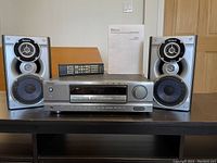 Sony AV receiver with left and right speakers, remote control, and instruction booklet displayed on table