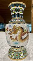 Front view of cloisonne vase showing detailed gold dragon design with cloud motifs on white enamel background
