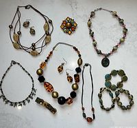 Overview photo showing all costume jewelry items on a light background, including necklaces, bracelets, earrings, and a brooch in earth tones.