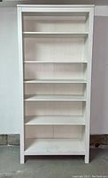 Front view of the tall white stain finish wooden bookcase with six shelves.