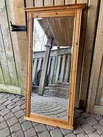 Full view of rectangular pine wall mirror outdoors showing natural pine frame with knots and clear mirror glass.