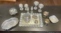 Photo showing a group of silver-plated items on a table including trays, a covered dish, shakers, small bowls, and small cups