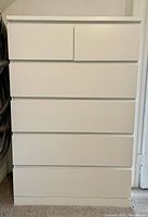 Front view of white six-drawer dresser showing two small top drawers and four larger bottom drawers.