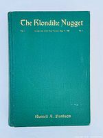 Front cover of The Klondike Nugget book with green buckram and gilt title and author name.