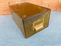 Image of the 1940's army green metal filing drawer showing top, side, and front with brass handle and label holder.