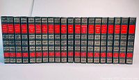 Front view of 20 volumes in navy leatherette with gilt decoration and red title blocks showing authors' names on the spines.