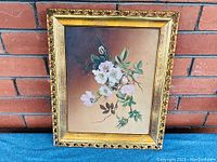 Front view of antique still life oil painting on canvas with gilded frame against brick background, showing floral bouquet artwork.