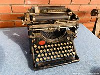 Front view of the antique Underwood typewriter showing keys, red badge, and paper holder with Underwood name.