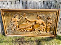 Full view of golden bas relief wall decoration showing reclining woman and cherubs