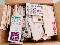Cardboard box filled with a large quantity of envelopes and first day covers.