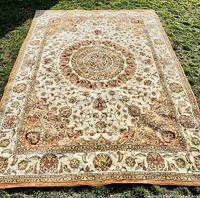 Full view of carpet laid flat on grass showing overall design and condition