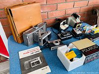 Full lot showing multiple vintage cameras, camera case, original packaging, and manuals