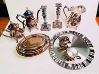 Seven-piece vintage silverplated tea set including teapot, sugar bowl, creamer, two candlesticks, covered vegetable dish, and a round tray with gravy boat and sauce boat
