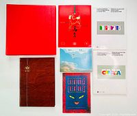 Photo showing multiple hardcover stamp albums and souvenir collections including Canada 1978 and 1979 sets, red and brown cover albums, and a booklet titled "Creatures".