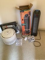 Full lot showing Honeywell air purifier with extra filters and Holmes tower heater with box and manuals, displayed on carpeted floor.