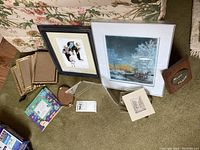 First image shows two framed art prints (a winter scene and a figure illustration), several empty frames of various sizes and materials, and a small magnetic acrylic block frame.