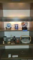 View of the entire collection displayed on shelf showing pottery items, ceramic basket, stone horse figure, and jars