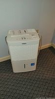 Full front view of the Tosot dehumidifier showing white plastic body, ventilation grill, and water level indicator.