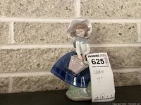 View of Lladro figurine showing front profile of girl in blue dress holding flower basket.