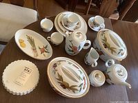 Porcelain dinnerware and serving set with colorful fruit and vegetable motif in classic Evesham pattern, shows all main components on wooden table.