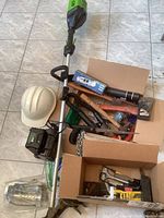 Full lot overview showing trimmer, white safety helmet, boxes with hand tools and accessories