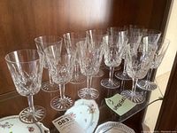 Thirteen Waterford Lismore water goblets arranged together showing varying stem thickness and cut pattern.