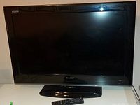 Front view of the Sharp Aquos 32-inch LCD TV with stand on a white surface.