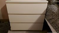 Front view of the white IKEA MALM dresser showing three drawers and its simple, modern design.