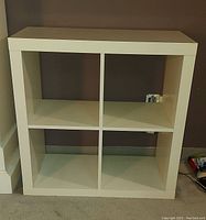 Front view of the 4x4 cube shelf unit showing 16 compartments in white veneer finish.
