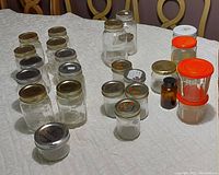 Full view of all 14 assorted glass canning jars and repurposed storage jars on quilted surface.