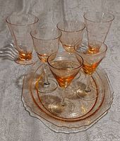 Full set showing three pairs of pink glasses and the pink patterned platter/tray arranged on a fabric background