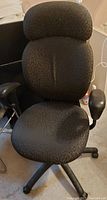 Front view of the office chair showing the black textured fabric upholstery on the seat and backrest with integrated headrest.