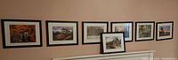 View of seven framed landscape photographs by Norman and Joanie Piluke hung on a wall. Each photograph is in a black frame with white matting, showing various nature landscapes in color and black and white.