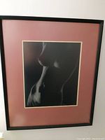 Framed black and white lithograph of a nude female torso by Tracy Valleau with dusty rose mat and black frame.