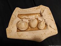 Front view showing the three tomatoes and artist signature in plaster relief