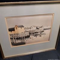 Close-up view of framed waterfront scene print showing buildings, dock, and boat