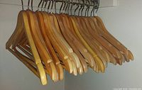Wooden clothes hangers, natural finish, arranged side by side on closet rod