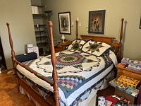 Full view of full size bed assembled with wood headboard, footboard, four tall posts, and bedding on top.