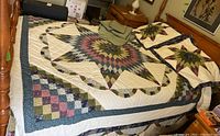 Photo of full-sized patchwork quilt bedspread with starburst design on bed and matching pillow shams.
